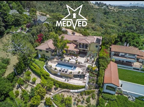 Betoverend uitzicht omringt elke centimeter van dit elegante, op maat gemaakte huis in de mediterrane Hollywood Hills met een indrukwekkend uitzicht in twee richtingen op zowel het LA-bekken als de San Fernando Valley. Ooit eigendom van Theodore Geis...