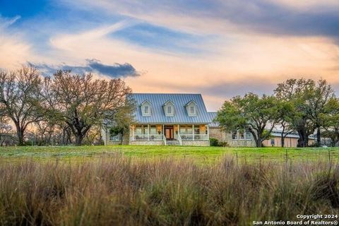 Quintessential Texas-style, stone-encased farmhouse with three gabled dormers, standing seam metal roof, and wide steps leading to a deep, covered front porch. Enjoy sweeping view of 35.68 fenced, ag-exempt acres with spring fed pond, it's cross-fenc...